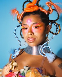 a woman in a colorful costume posing in front of a blue background